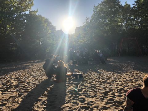 a group of people sitting in the sand. Sun is shining