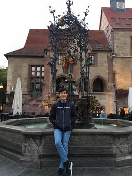 Jun stands in front of an old fountain in Göttingen.