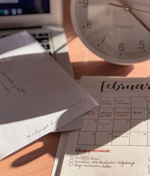 A Calendar, notes, clock and laptop on a desk