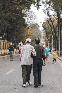 Two elderly men walk arm in arm down a street, picture taken in Hanoi, Vietnam.