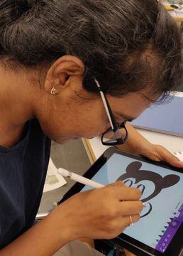 Sreehitha paints a Mickey Mouse image on a tablet