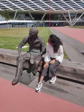 Sreehitha sits next to a statue in front of a stadium