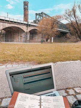 An open Laptop and studying material in front of a bridge