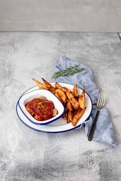 Dish of curry sausage with sweet tomato sauce and oven potato wedges
