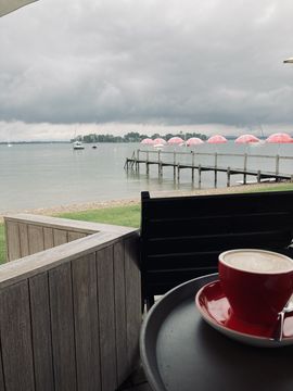 The view of the Chiemsee from the terrace of a café, you can still see a cup of coffee.