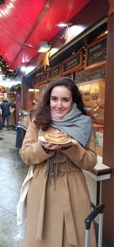 A woman holding a pastry, visiting a Christmas market.