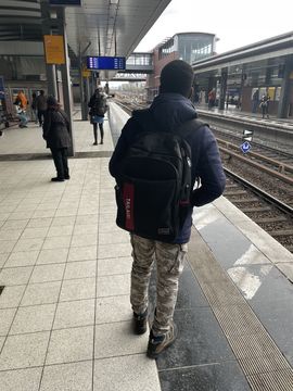 A student stands on a platform at a German train station and waits for his train.