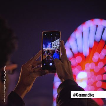 Social Media Format #GermanSite als Einsendung von Testimonial. Ein Riesenrad wird bei Nacht mit einem Smartphone fotografiert.