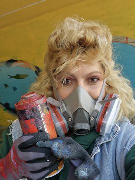 Lilit wears a respirator and a protective suit to be well protected when spraying graffiti.