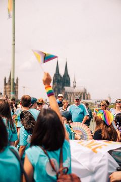 A person waving a rainbow flag in front of a crowd