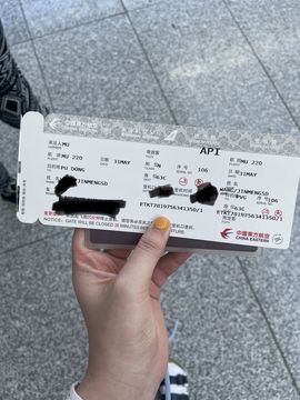 A hand holding a boarding pass for a flight from Frankfurt to Shanghai.