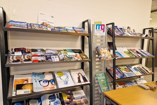 A shelf with flyers. The Info Point of Flensburg University, with a counseling booth and many brochures.