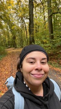 A selfie that Elisa took of herself in hiking clothes during the hike. The autumnal forest can be seen in the background.