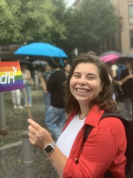 Elisa with a little pride flag, smiling broadly.